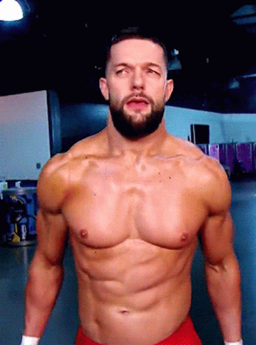 A Shirtless Wrestler With A Beard Is Standing In A Gym GIF