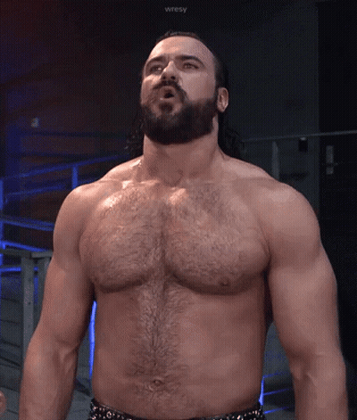 A Shirtless Wrestler With A Beard Is Standing In Front Of A Sign That Says Wresty GIF