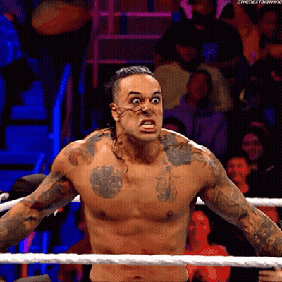 A Shirtless Wrestler With A Tattoo On His Chest Is Standing In The Ring GIF