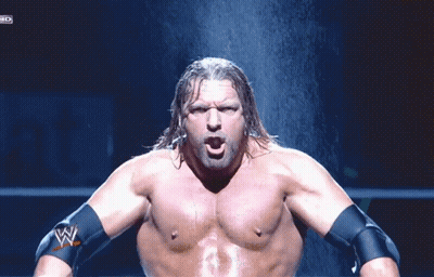 A Shirtless Wrestler With A W Logo On His Arm Stands In Front Of A Waterfall GIF