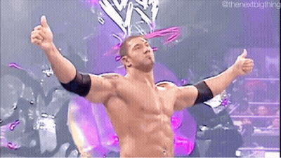A Shirtless Wrestler With His Arms Outstretched In Front Of A Purple Background . GIF