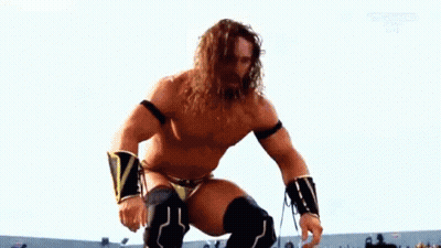 A Shirtless Wrestler With Long Hair And A Beard Is Kneeling Down On A Ring . GIF