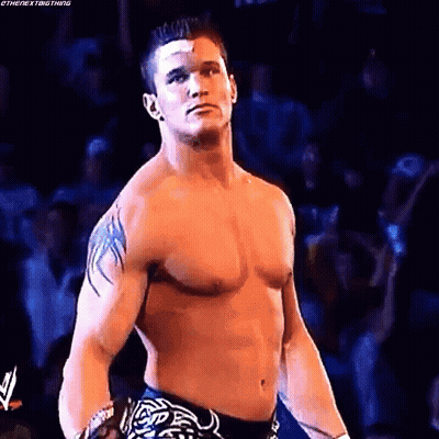 A Shirtless Wrestling Wrestler With A Bandage On His Forehead Is Standing In Front Of A Crowd . GIF