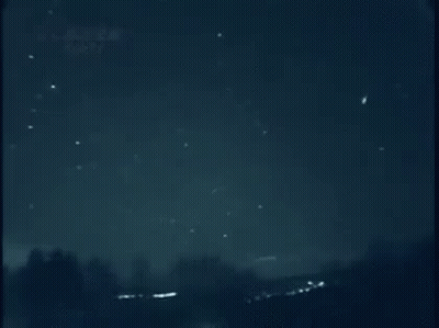 A Shooting Star Is Flying Through A Dark Night Sky . GIF
