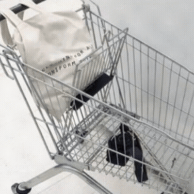 A Shopping Cart With A Tote Bag That Says Uniform On It GIF
