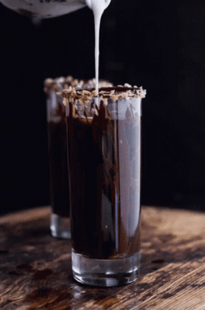 A Shot Glass Filled With Chocolate And Whipped Cream Being Poured Into It GIF