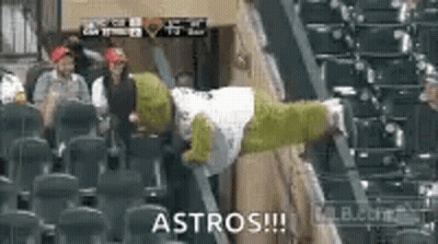 A Shrek Mascot Is Sitting In The Stands At A Baseball Game With A Group Of People . GIF