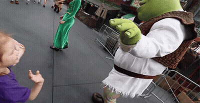 A Shrek Mascot Standing Next To A Little Girl In A Purple Shirt GIF