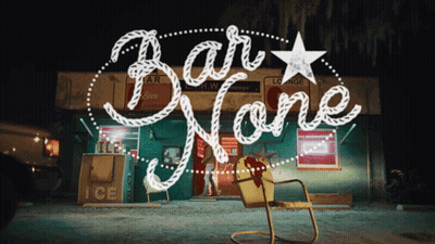 A Sign For Bar None With A Yellow Chair In Front Of It GIF