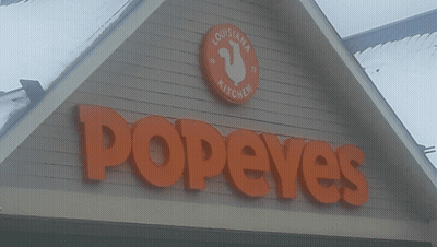 A Sign For Popeye 'S Louisiana Kitchen Is On A Building GIF