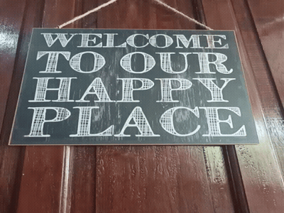 A Sign Hanging On A Wooden Wall Says Welcome To Our Happily Place GIF