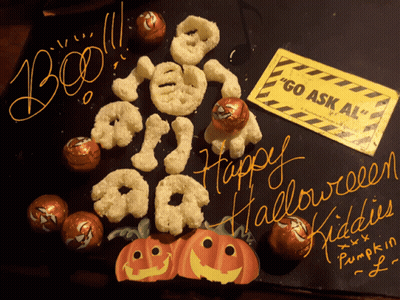 A Sign That Says " Go Ask Al " Sits Next To A Display Of Halloween Treats GIF