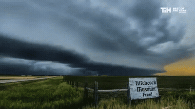 A Sign That Says Hitchcock Museum Free In Front Of A Storm GIF
