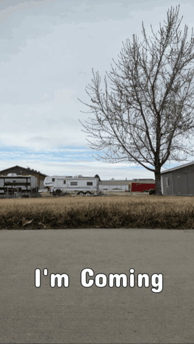 A Sign That Says " I 'M Coming " With A Tree In The Background GIF