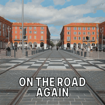 A Sign That Says On The Road Again In Front Of A Busy Street GIF
