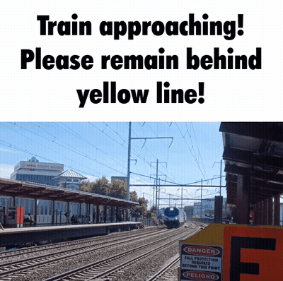A Sign That Says " Train Approaching Please Remain Behind Yellow Line " Next To A Picture Of A Train GIF