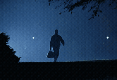 A Silhouette Of A Man Carrying A Bag In A Dark Field GIF