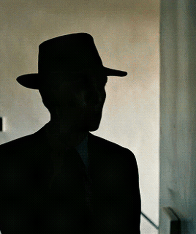 A Silhouette Of A Man In A Hat And Suit GIF