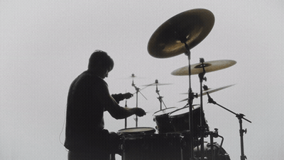 A Silhouette Of A Man Playing Drums With A White Background GIF
