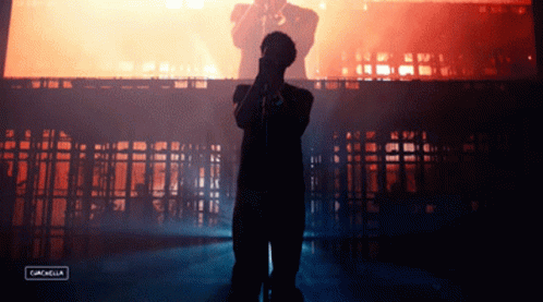 A Silhouette Of A Man Singing Into A Microphone With The Words Coachella On The Bottom GIF