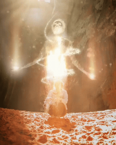 A Silhouette Of A Man Sitting In The Sand With A Light Coming Out Of His Head GIF