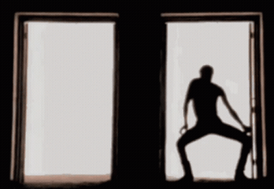 A Silhouette Of A Man Standing In An Open Door GIF