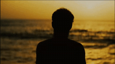 A Silhouette Of A Man Standing In Front Of The Ocean At Sunset GIF