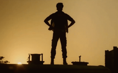 A Silhouette Of A Man Standing With His Hands On His Hips At Sunset GIF