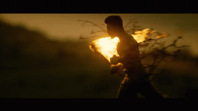 A Silhouette Of A Person Holding A Torch In A Field GIF
