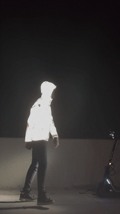 A Silhouette Of A Person In A Reflective Jacket Is Visible In The Dark GIF