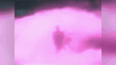 a silhouette of a person is walking through a pink foggy field .