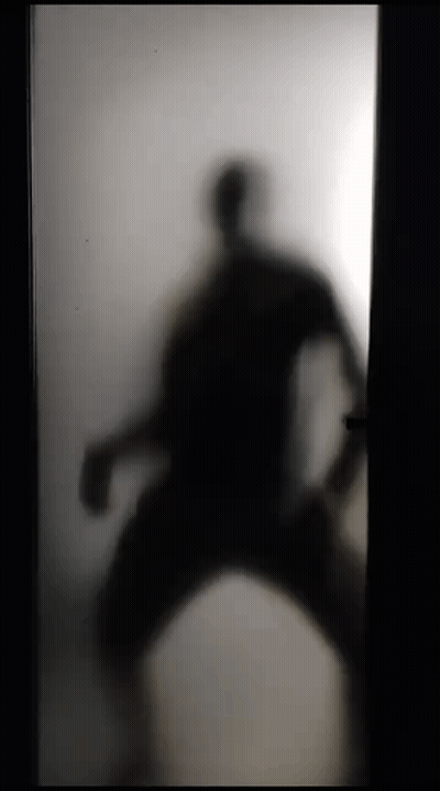 A Silhouette Of A Person Standing In A Doorway Behind A Frosted Glass Door . GIF