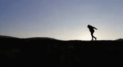 A Silhouette Of A Person Standing On Top Of A Hill . GIF