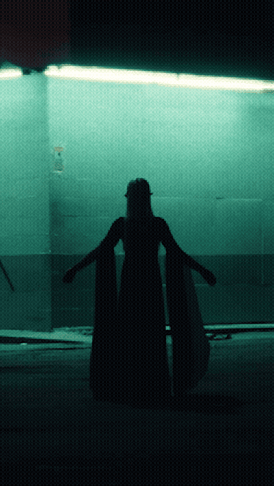 A Silhouette Of A Woman In A Long Dress Stands In Front Of A Sign That Says No Smoking GIF