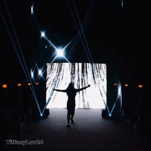 A Silhouette Of A Woman Standing In Front Of A Large Screen With Tiffanyluv24 Written On The Bottom Right GIF
