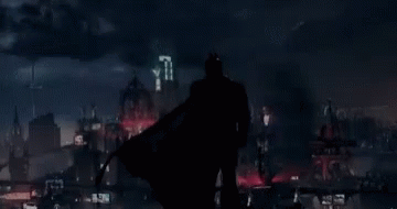 A Silhouette Of Batman Is Standing In Front Of A City GIF