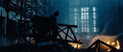 A Silhouette Of Batman Standing On A Bridge In Front Of A Building GIF
