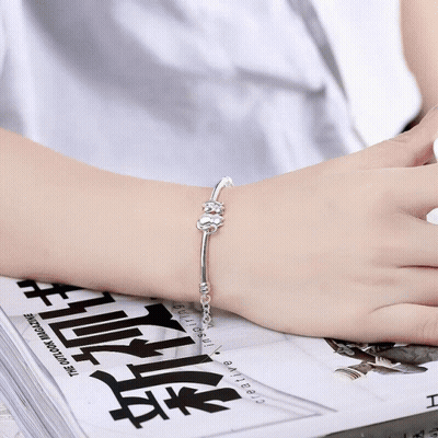 A Silver Bracelet With Two Cats On A Chain GIF