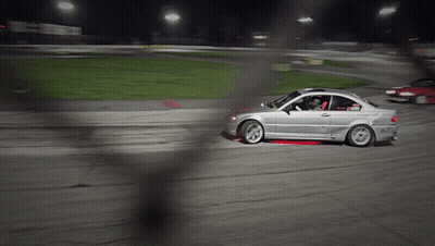 A Silver Car Is Driving On A Dirt Road At Night GIF