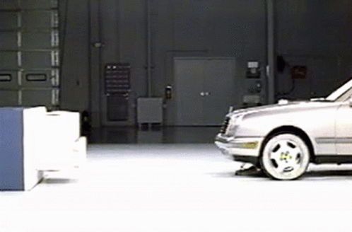 A Silver Car Is Parked In A Garage In Front Of A Door . GIF