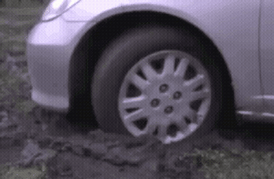 A Silver Car Is Stuck In A Muddy Area . GIF