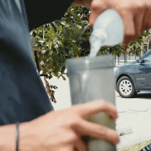 A Silver Chevy Equinox Is Parked In The Background As A Person Pours Water Into A Cup GIF