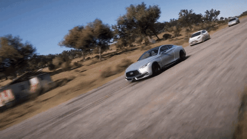 A Silver Infiniti Car Is Driving Down A Road GIF