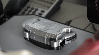 A Silver Item With The Letter D On It Sits On A Desk Next To A Phone GIF
