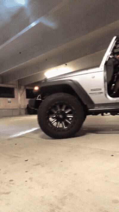 A Silver Jeep Is Parked In A Parking Garage With The Door Open GIF