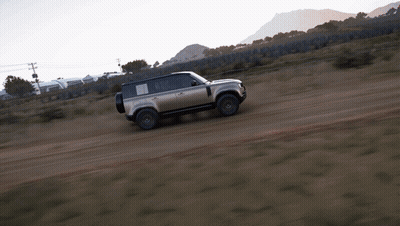 A Silver Land Rover Is Driving On A Dirt Road GIF