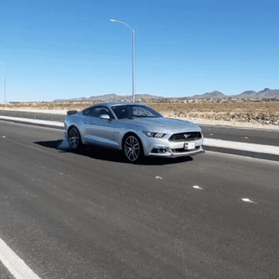 A Silver Mustang Is Driving Down A Desert Road GIF