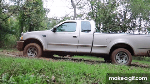 A Silver Pickup Truck Is Parked In A Grassy Field With Trees In The Background And The Words Make A Gif.com Below It GIF