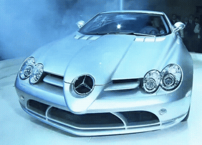 A Silver Sports Car With A Mercedes Logo On It GIF