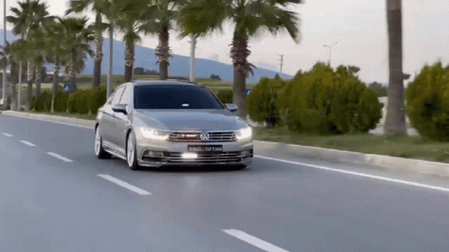 A Silver Volkswagen Car Is Driving Down The Road GIF